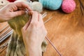 A woman knits a wool thing with spokes. Hands close-up