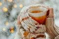 Woman in knitted mittens drinking hot tea on snowy background with lights. Royalty Free Stock Photo