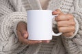 Woman in knitted sweater holding white mug in hands. Winter cup Mockup for Christmas individual gifts design Royalty Free Stock Photo