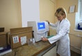 Woman lab assistant in white coat working with the hematology analyzer. Laboratory of a hospital. Kyiv, Ukraine Royalty Free Stock Photo