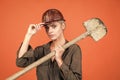 woman laborer in protective helmet and boilersuit hold shovel on orange background, construction Royalty Free Stock Photo