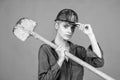 woman laborer in protective helmet and boilersuit hold shovel on orange background, construction Royalty Free Stock Photo