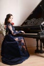 Woman in lace deep blue dress playing the piano and flowers. Retro vintage style Royalty Free Stock Photo