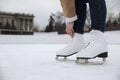 Woman lacing figure skate on ice rink, closeup. Space for text Royalty Free Stock Photo