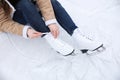 Woman lacing figure skate while sitting on ice  closeup Royalty Free Stock Photo