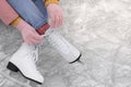 Woman lacing figure skates on ice, closeup. Space for text Royalty Free Stock Photo