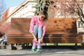 Woman lacing roller skates while sitting on bench outdoors Royalty Free Stock Photo