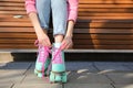 Woman lacing roller skates while sitting on bench outdoors, closeup Royalty Free Stock Photo