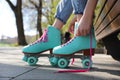 Woman lacing roller skates while sitting on bench outdoors, closeup Royalty Free Stock Photo