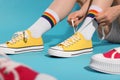 Woman lacing up yellow classic old school sneakers against light blue background, closeup Royalty Free Stock Photo