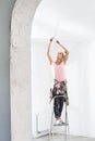 Woman on ladder fitting light bulb in new house