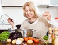 Woman with ladle cooking soup in pan in home kitchen