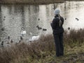Woman on the lake feeds ducks and swans