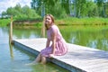 Woman on the lake on the pier sits resting in the summer. Royalty Free Stock Photo