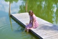 Woman on the lake on the pier sits resting in the summer. Royalty Free Stock Photo