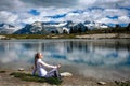 Woman on the lake shore meditating and relaxing. Beautiful view of mountains and reflections in the lake. Royalty Free Stock Photo