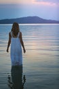 Woman in lake waters looks at soft purple sunset