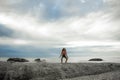 Woman landing on a rock at sunset on Bakovern Beach, Cape Town.