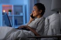 woman with laptop calling on phone in bed at night Royalty Free Stock Photo