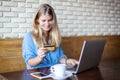 Woman with laptop and credit card in cafe . Online payment, digital banking. Young girl shopping Royalty Free Stock Photo