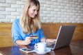 Woman with laptop and credit card in cafe . Online payment, digital banking. Young girl shopping