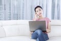 Woman with laptop daydreaming on couch Royalty Free Stock Photo