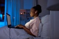 woman with laptop and earphones in bed at night Royalty Free Stock Photo