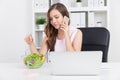 Woman with laptop eating salad Royalty Free Stock Photo