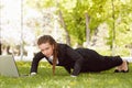 Young woman with laptop lying in the green grass