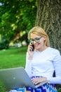 Woman with laptop in park order item on phone. Girl takes advantage of online freelance job. Girl sit grass with Royalty Free Stock Photo