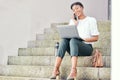 Woman, laptop and phone call for remote work on stairs with thinking, smile and ideas for networking. Freelance