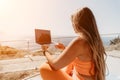 Woman laptop sea. Working remotely on seashore. Happy successful woman female freelancer working on laptop by the sea at Royalty Free Stock Photo