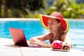 Woman with laptop at swimming pool. Remote work
