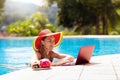 Woman with laptop at swimming pool. Remote work