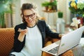 Woman with laptop talking on phone in modern house in sunny day Royalty Free Stock Photo