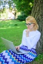 Woman with laptop works outdoor, park background. Girl sit grass lean tree trunk with notebook. Wi fi network connection Royalty Free Stock Photo