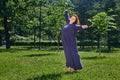 Woman of Large Build is dancing on lawn in park. Royalty Free Stock Photo