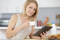 woman laughing at kitchen table with coffee and tablet