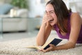 Woman laughing loud reading a paper book at home