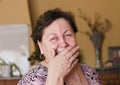 The woman laughs,covering her mouth with her hand