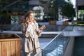 Woman laughs during phone call. Businesswoman talking on her telephone, standing in beige suit outside business center Royalty Free Stock Photo