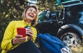 Woman laughter video calling on mobile phone in summer forest. Happy tourist smiling with backpack calling on cellphone