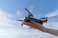 Woman launches the drone from the palm of her hand. Takeoff the quadcopter against the sky