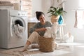 Woman with laundry basket near washing machine at home