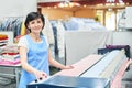 Woman Laundry worker pats the linen on the automatic machine