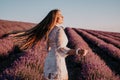 Woman lavender field. Happy carefree woman in a white dress walking in a lavender field and smelling a lavender bouquet Royalty Free Stock Photo