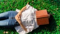 Woman lay down or relaxing on green grass at park and cover her face by a book in summer or spring, top view Royalty Free Stock Photo