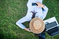 Woman lay down sleep on green grass meadow garden summer sunshine day happy time outside. Hipster Freelance work on laptop use hat Royalty Free Stock Photo