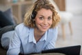woman layed on sofa using laptop and wearing headset Royalty Free Stock Photo
