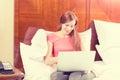 Woman laying in bed relaxing using working on her laptop computer Royalty Free Stock Photo